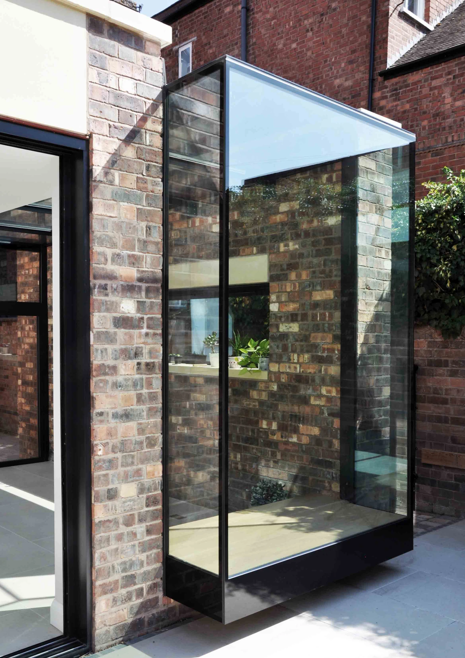 Oblique view of the projecting glass bay, showing its glass corner, roof and raised base.