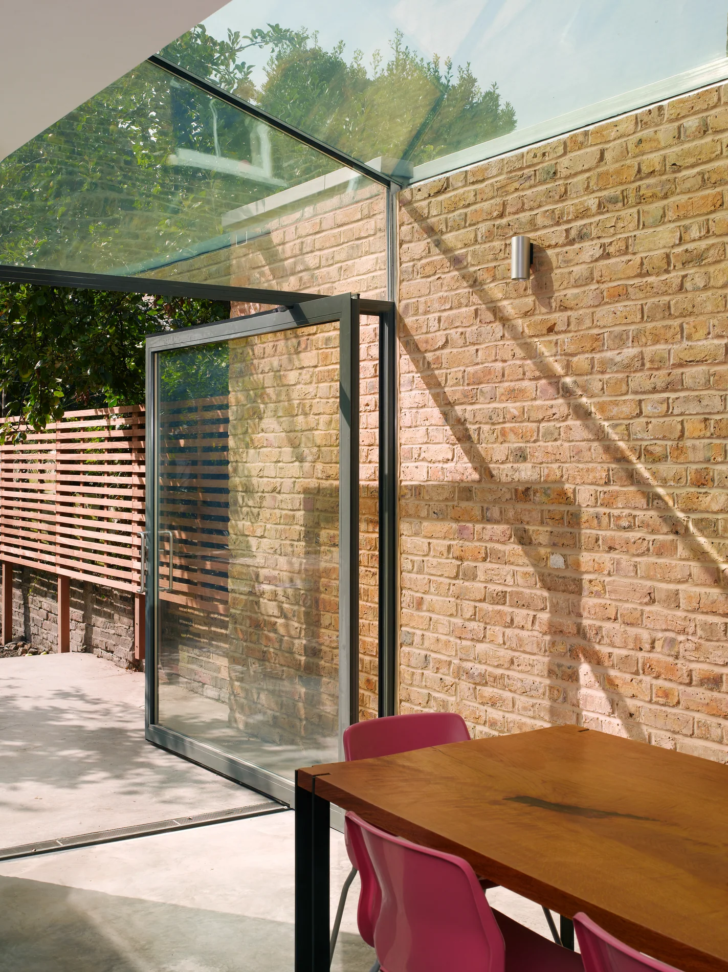 X-Max steel-inspired pivot door beside brickwork and structural glass