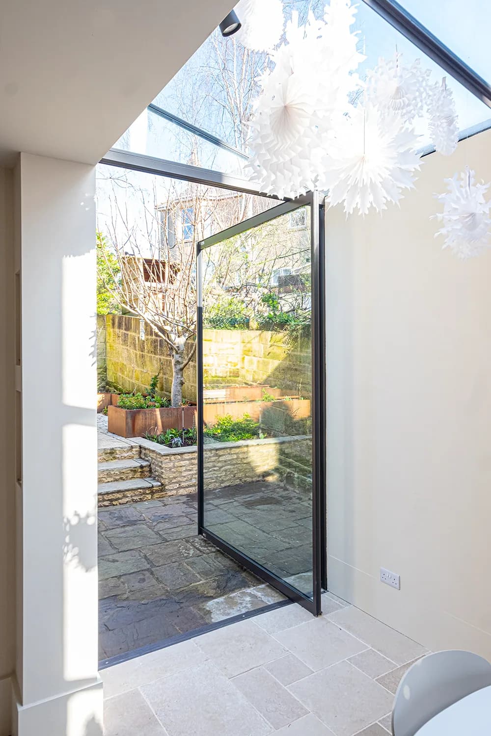 F-Max pivot door opening from a light interior to a paved garden
