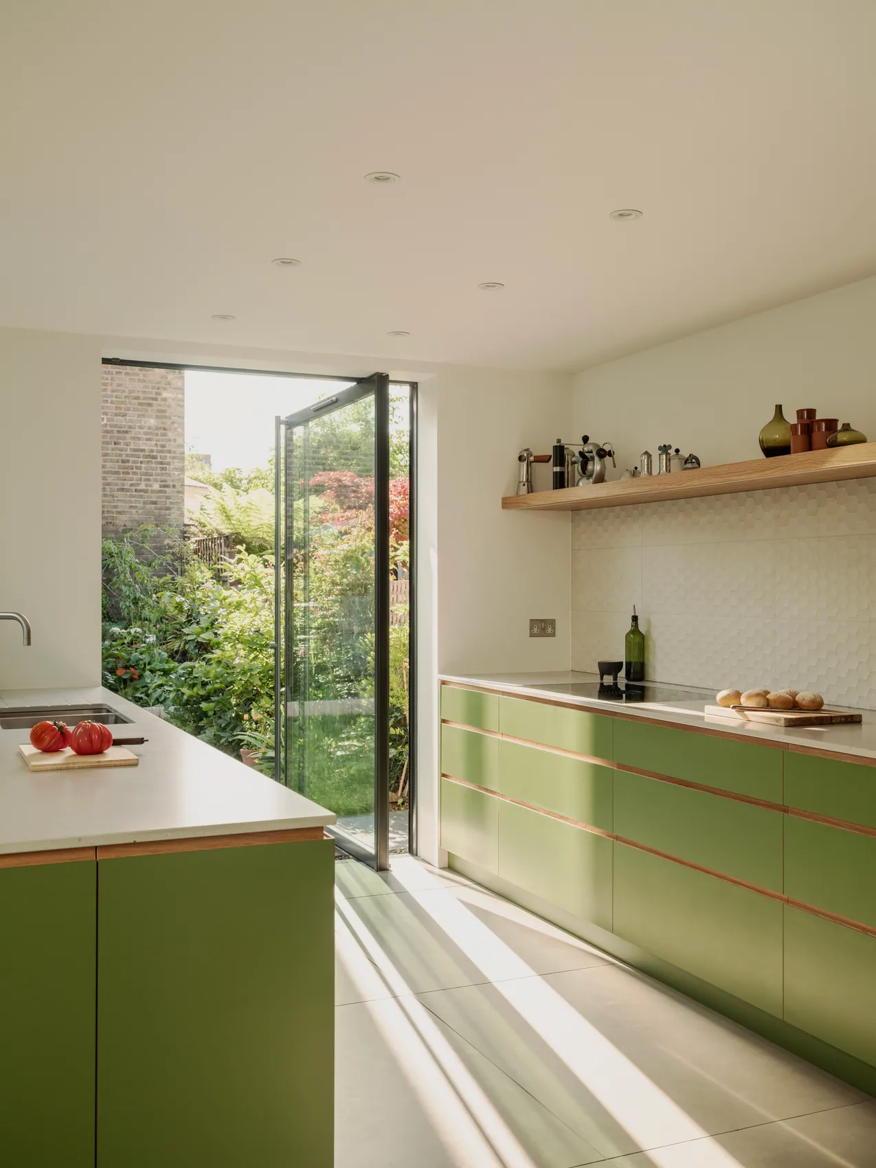 S-Max pivot door in a green kitchen opening towards planting