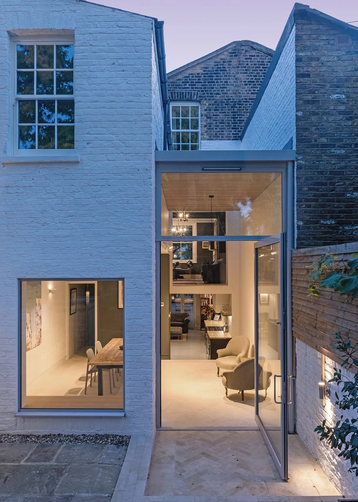 X-Max pivot door glowing at dusk in a contemporary house elevation