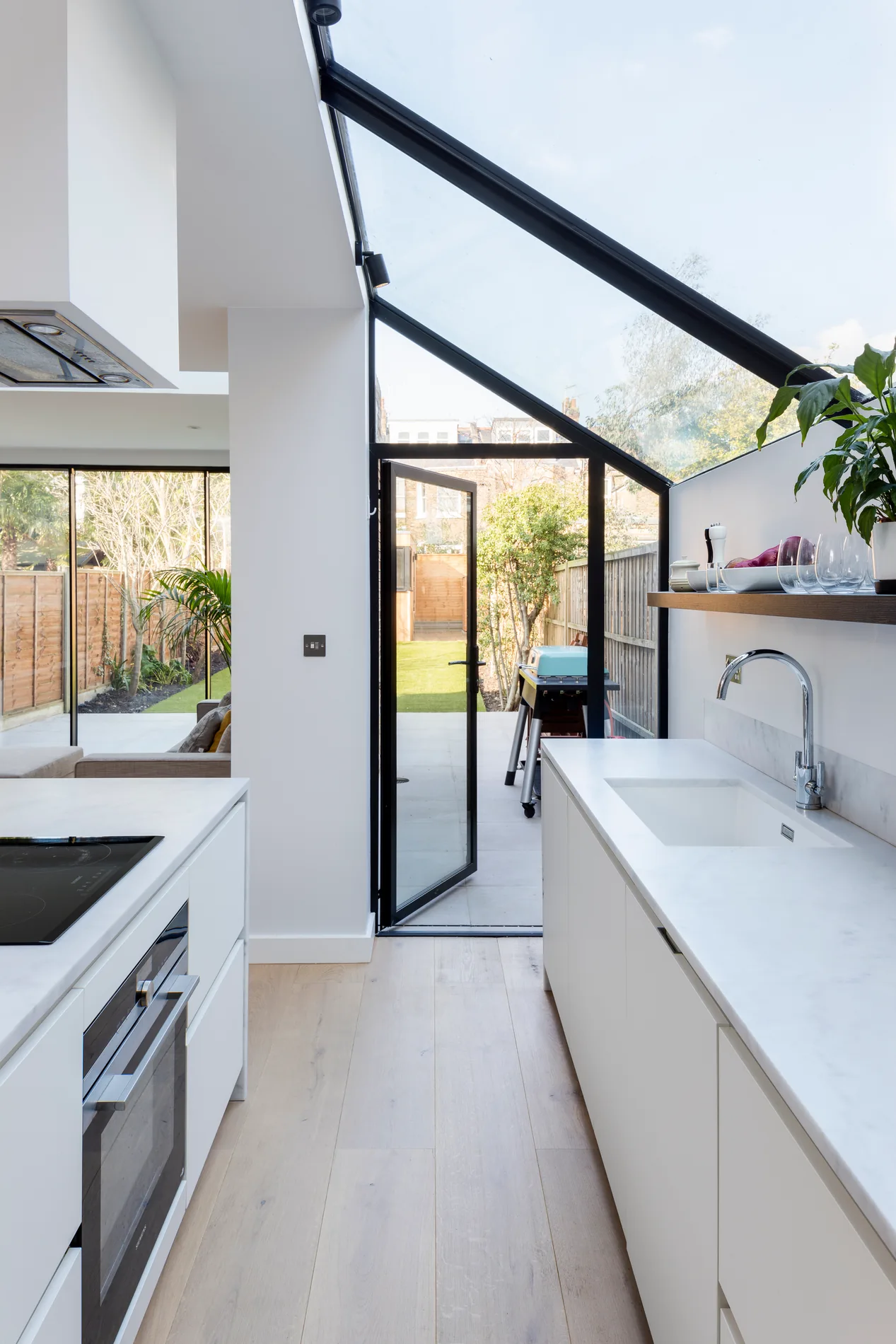 Lean-to glazed roof above a kitchen beside a brick wall and garden opening