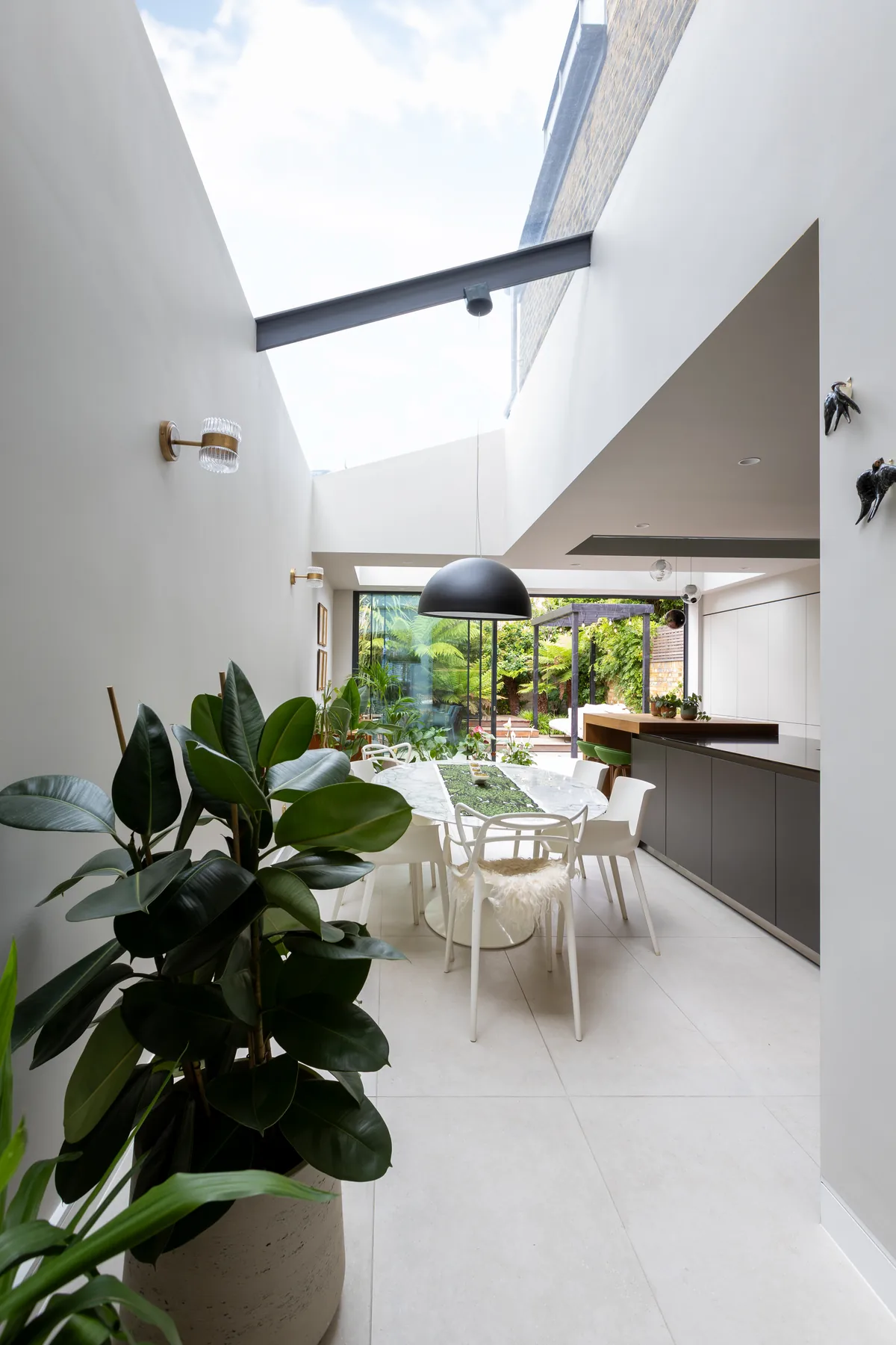 Dining space beneath a lean-to rooflight with garden views beyond