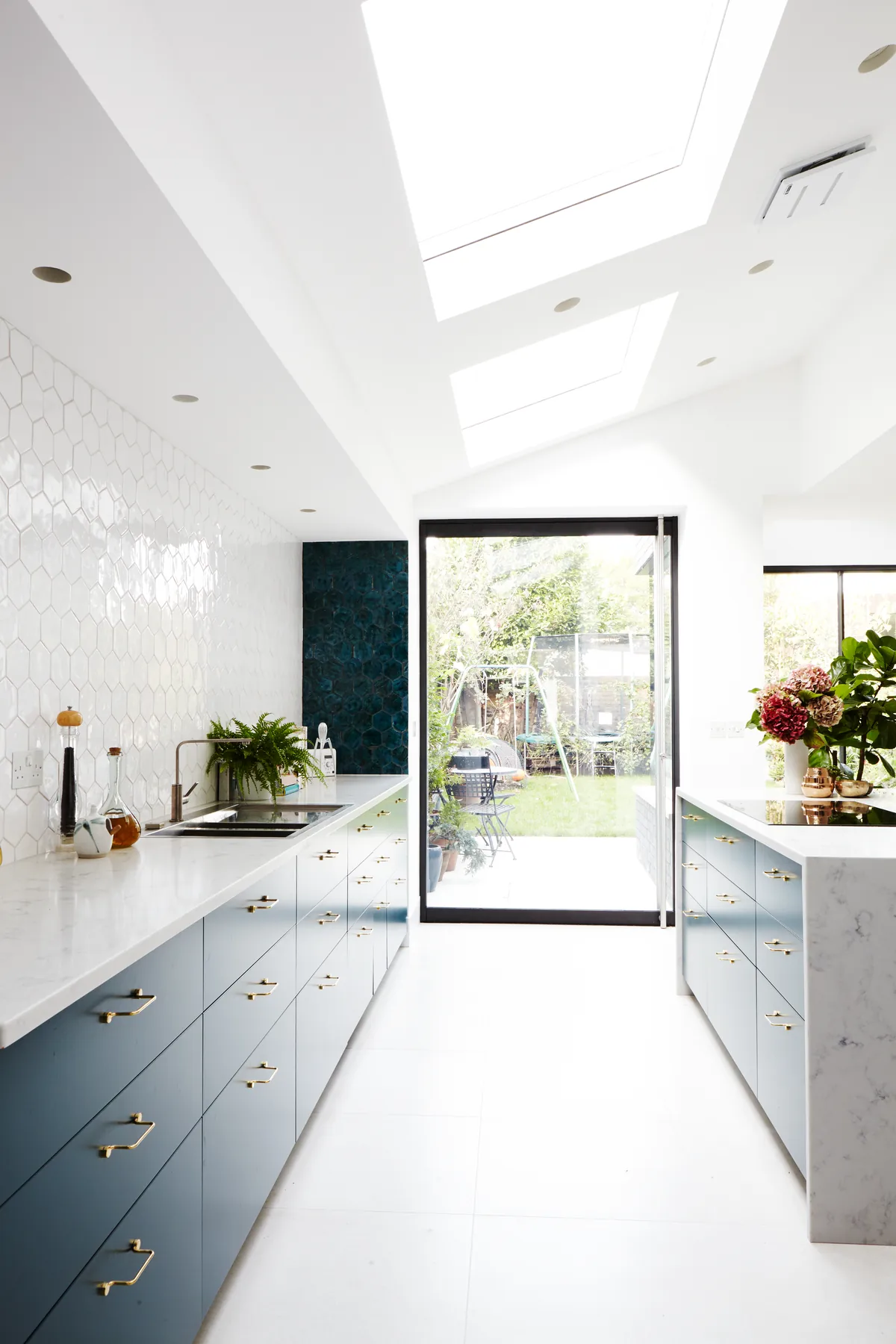 White contemporary kitchen lit by a concealed overhead rooflight