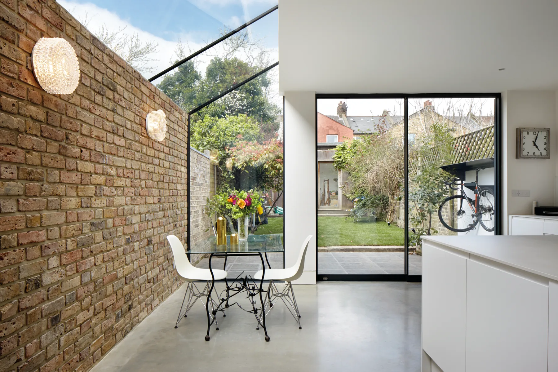 Up-and-over glazed roof running beside an exposed brick wall and dining space