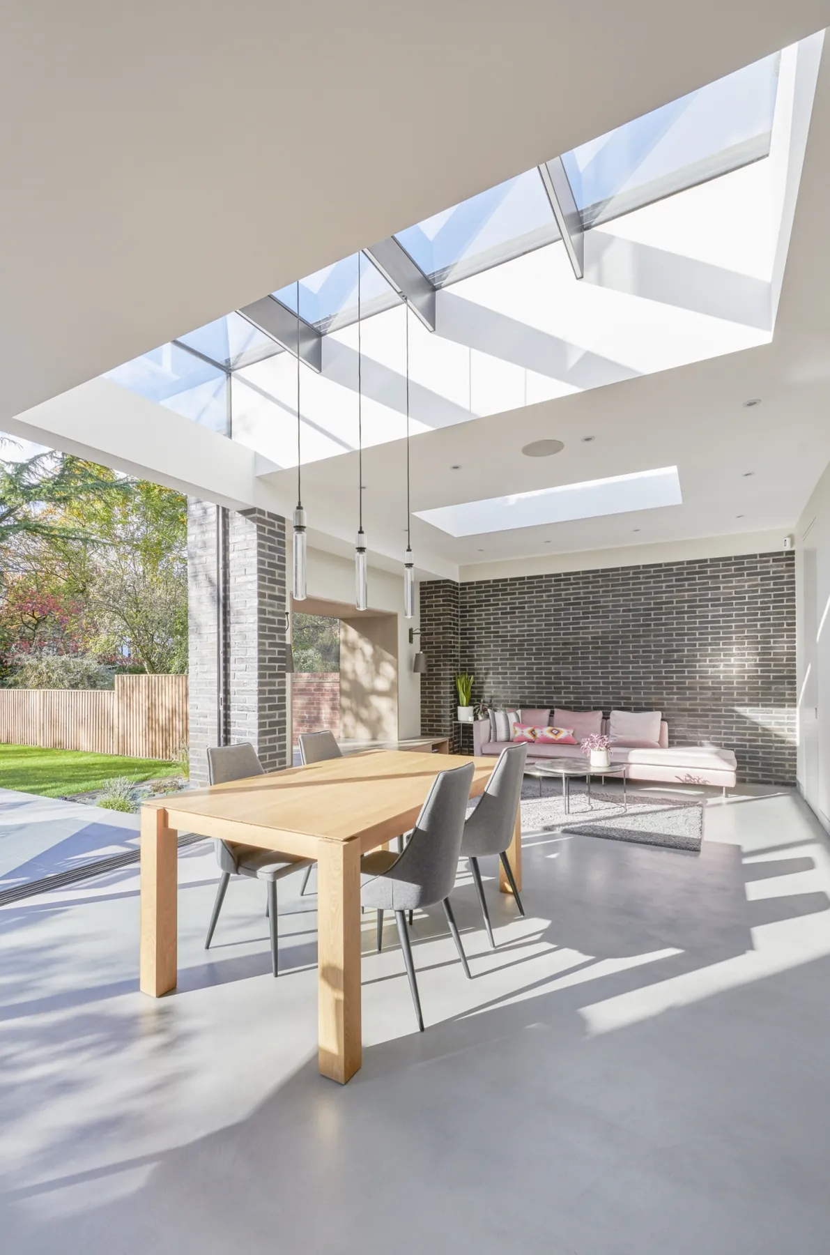 Bright living space with roof glazing above a dining table and garden view