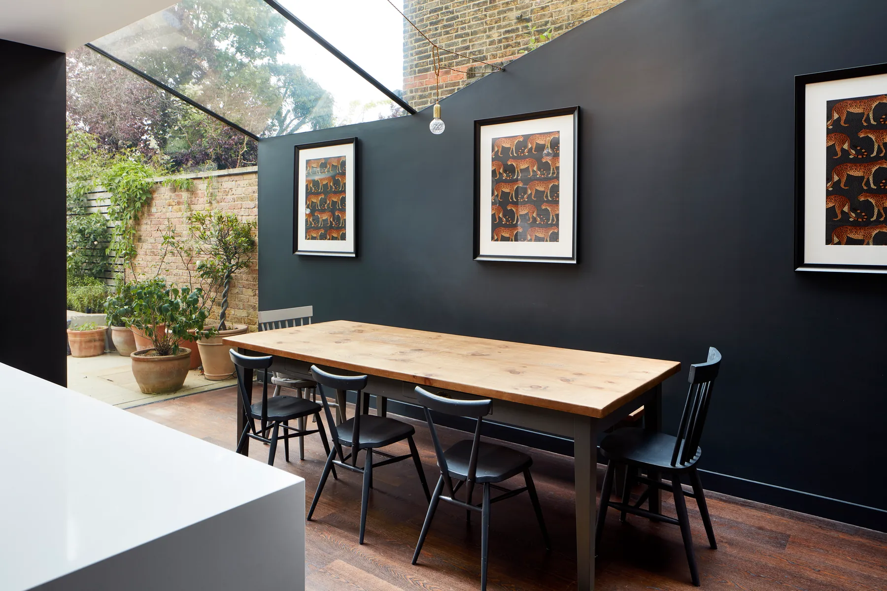Dark dining room with framed artwork below a glazed roof edge