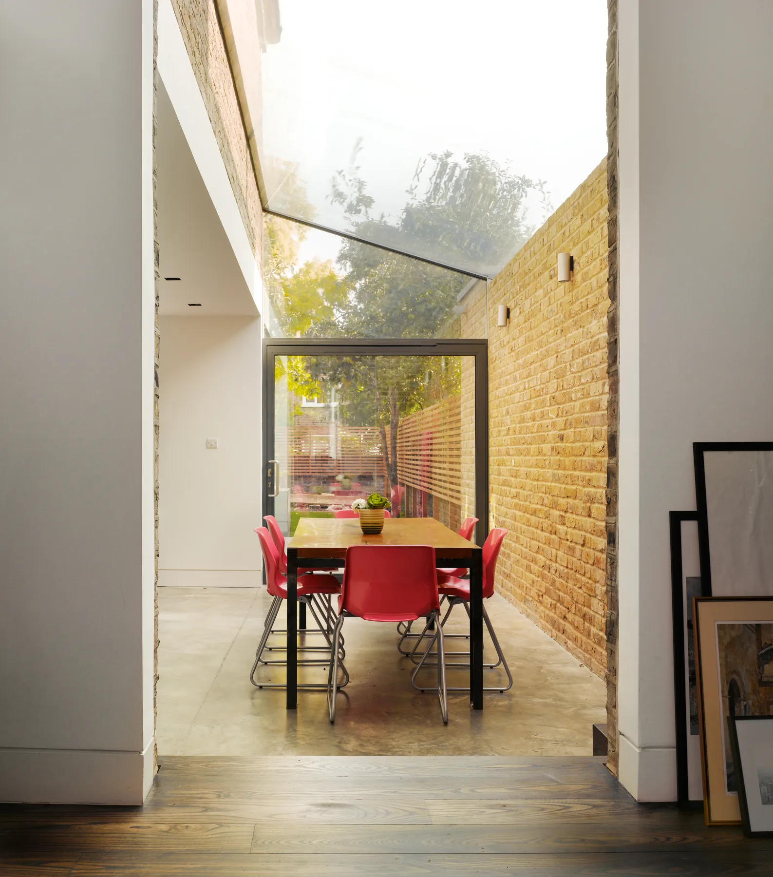 Red dining chair beside a glazed roof slot and brick wall