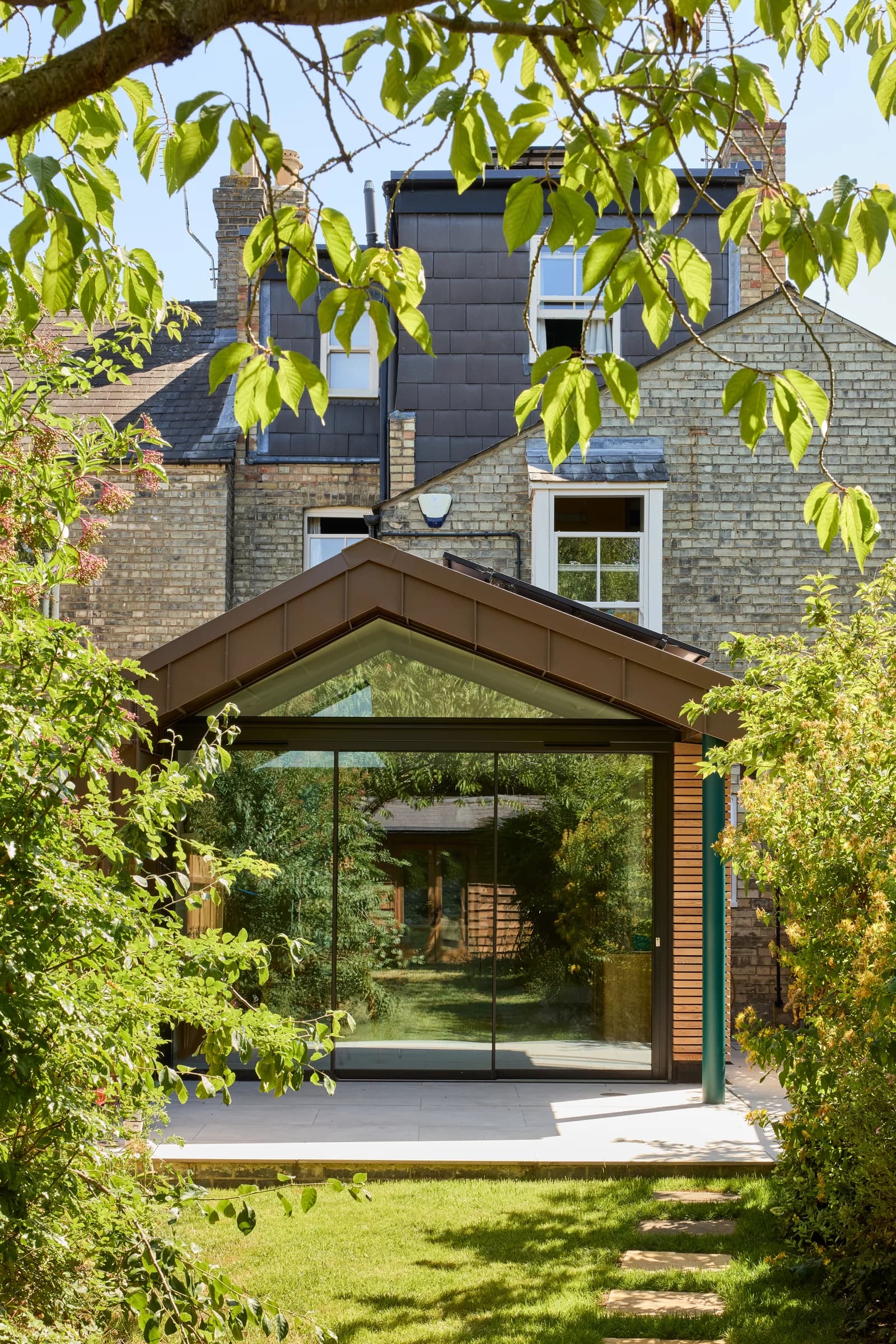Ultra-slim aluminium sliding doors across a garden extension framed by mature planting