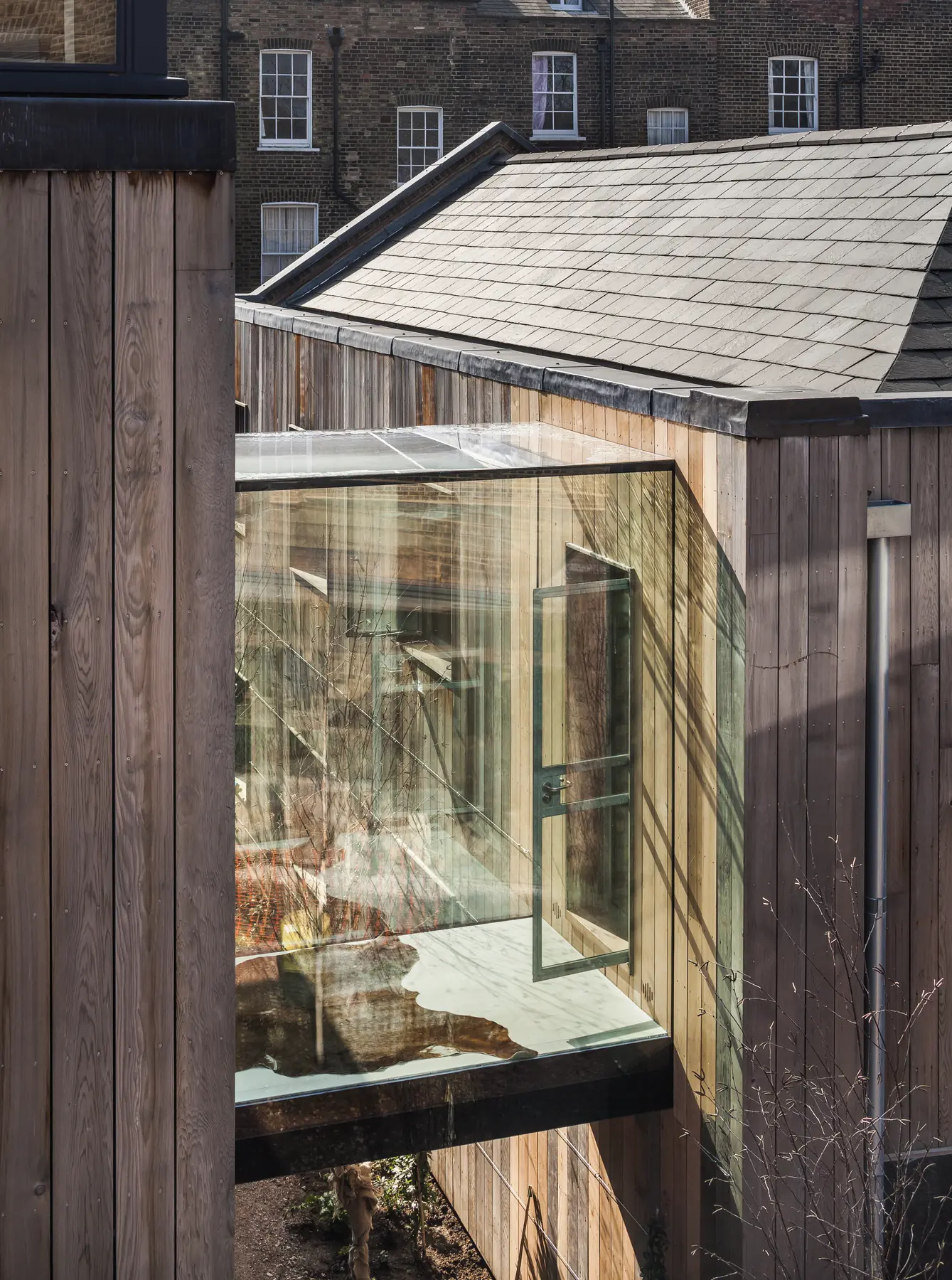 Structural glass box extension with frameless side return beside timber cladding