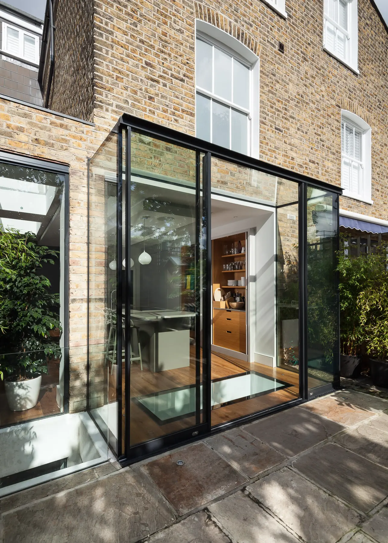 Glass extension corner with slim vertical glazing and garden planting