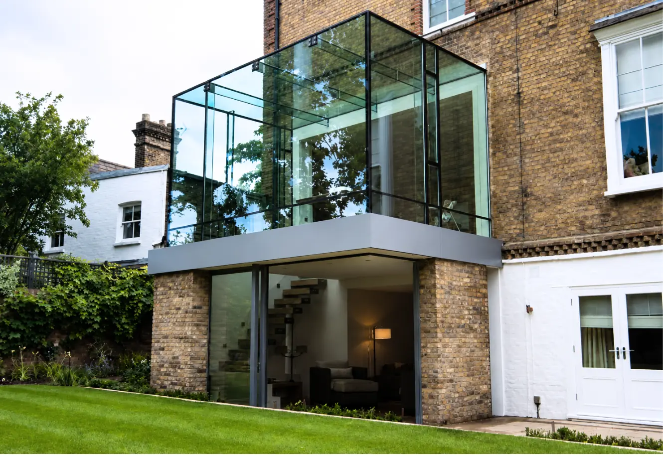 Upper-level glass box extension projecting from a brick home