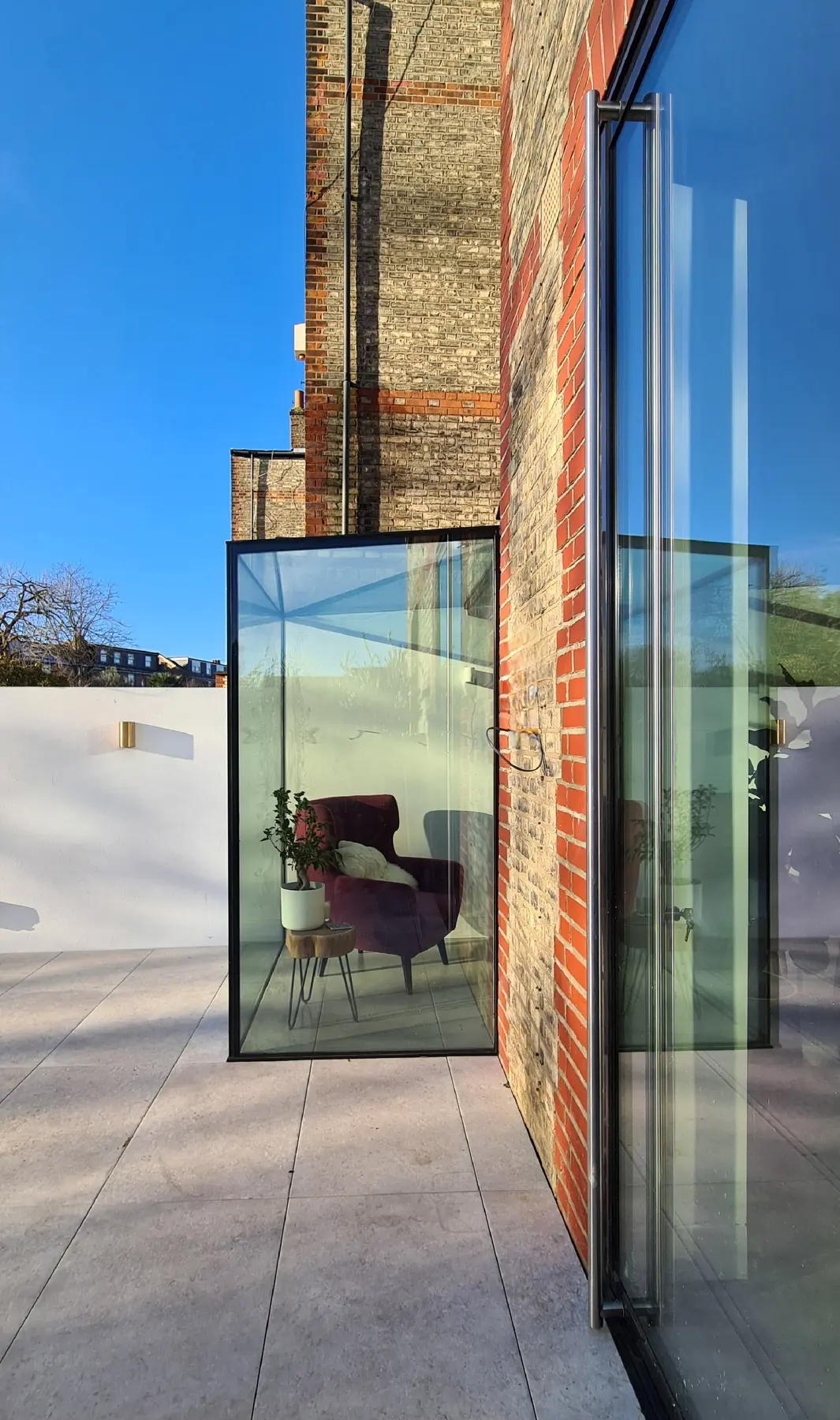 Glass box corner detail with clear structural glazing beside brickwork