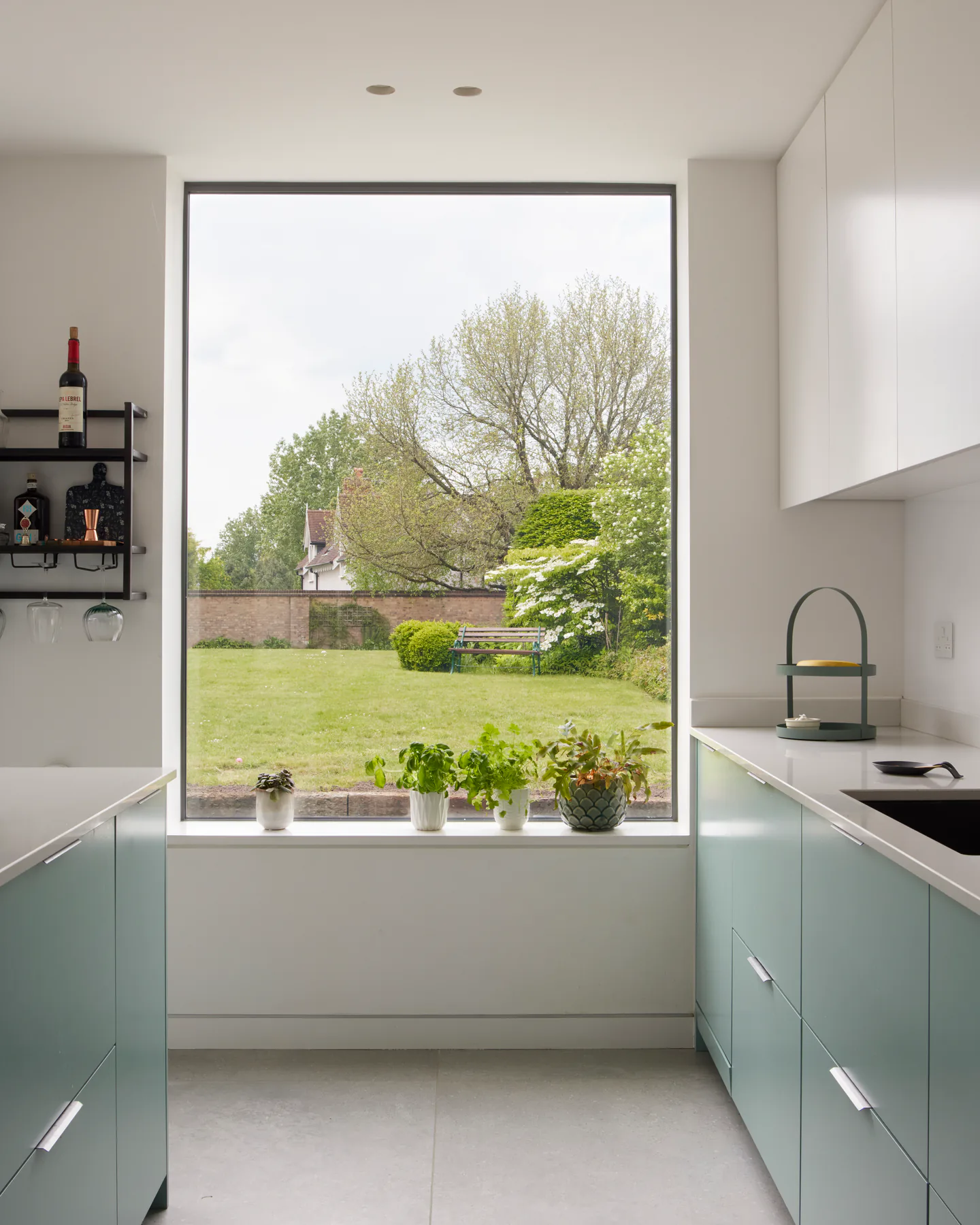 Fixed aluminium picture window above a kitchen sink framing a garden view