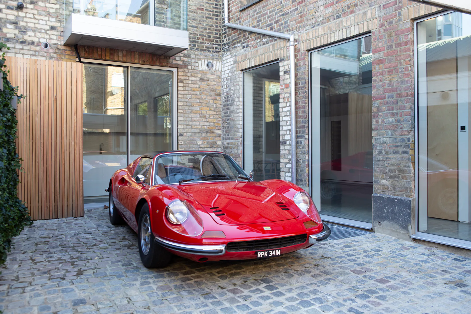 Full-height fixed aluminium windows enclosing a brick courtyard beside timber cladding