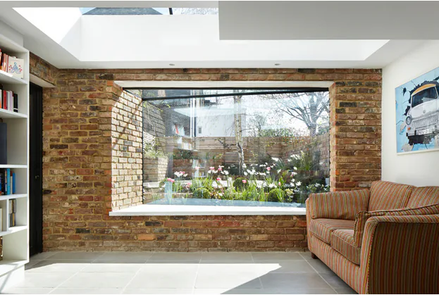 Deep-set oriel bay window framed by exposed brick inside a bright room