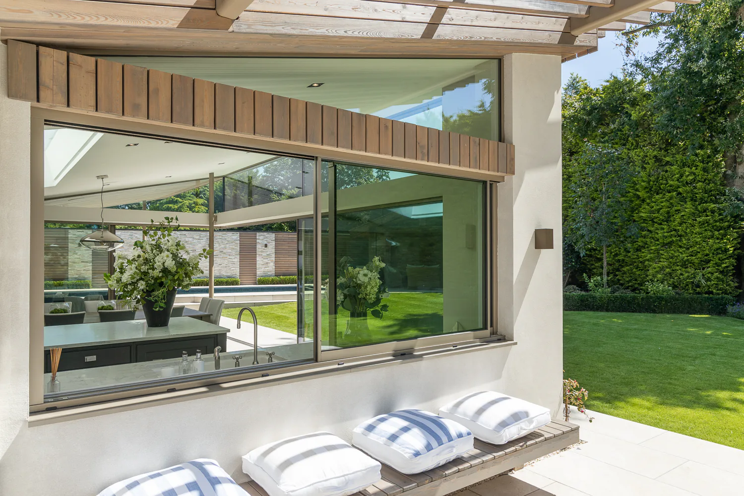 Wide aluminium sliding window opening a kitchen towards a garden