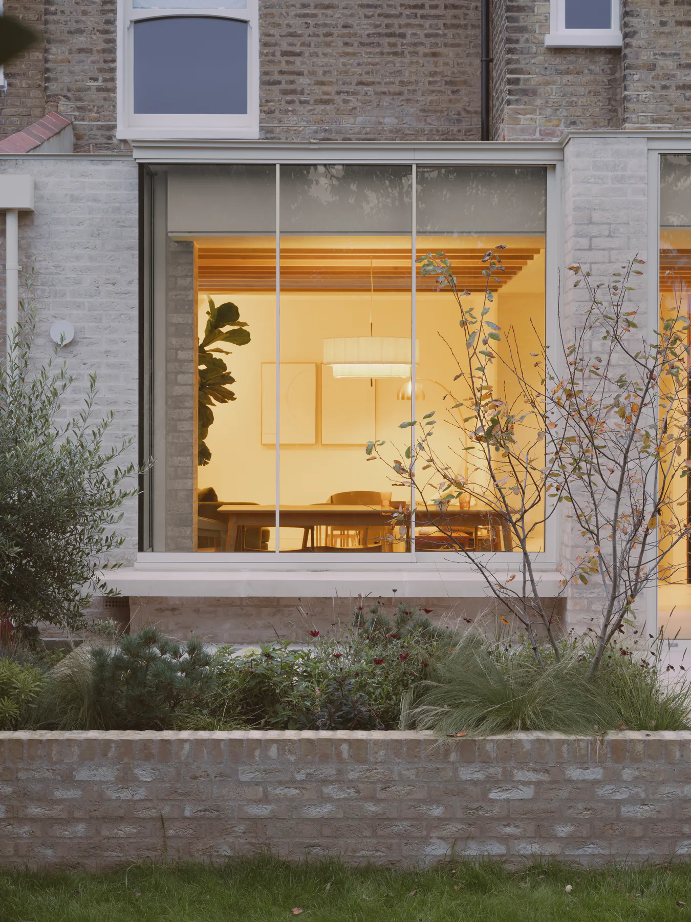 Illuminated sliding window within a restrained brick garden extension